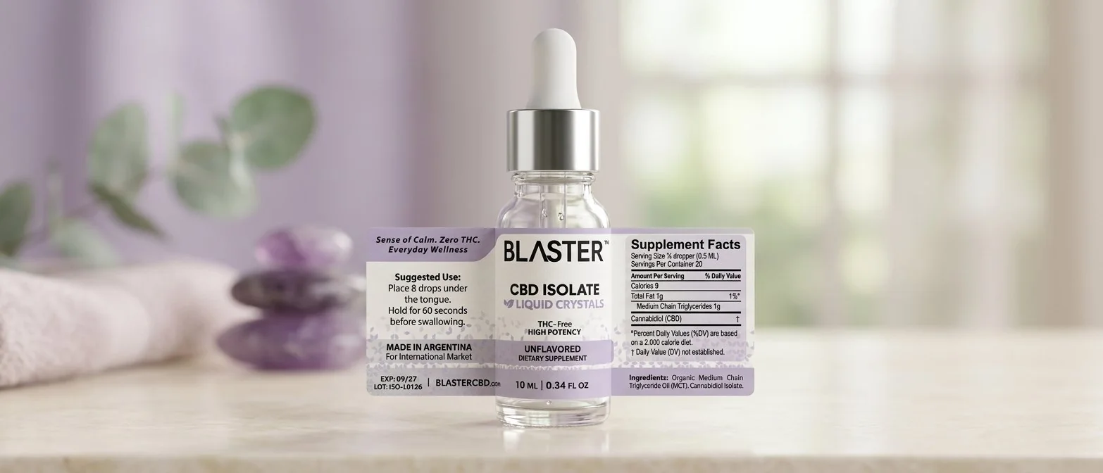 Frasco de 10 ml BLASTER™ ISOLATE con gotero blanco y etiqueta lila, sobre una mesa clara con piedras de amatista